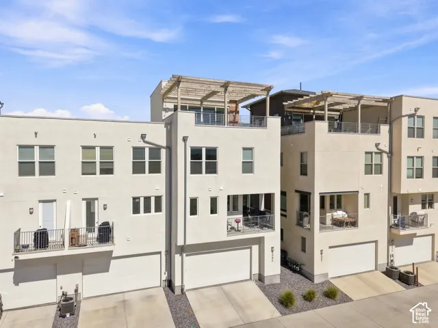 Modern stucco exterior with multiple balconies, rooftop pergolas, and integrated garages