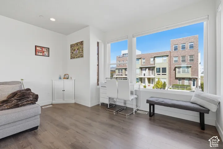 Expansive window wall, recessed lighting, wood-finish flooring, built-in corner cabinetry, crisp white walls