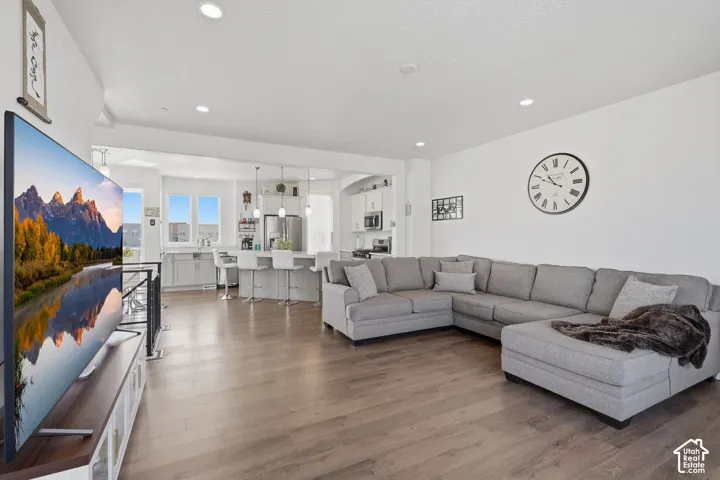Open-concept living space featuring wood-finish flooring, recessed lighting, and a kitchen with an island and pendant lights