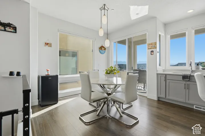 Wood-finish flooring, white walls, and a multi-light pendant fixture