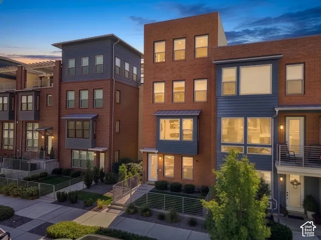 Multi-level townhome featuring a brick and siding exterior, multiple balconies, and a distinctive flat roofline