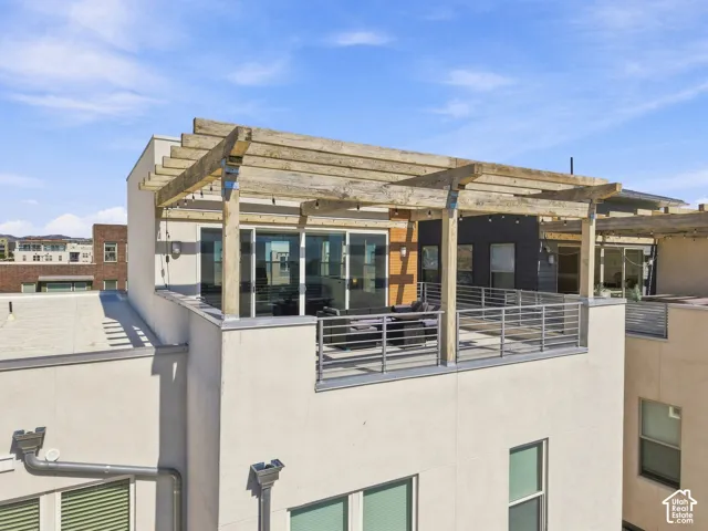Rooftop terrace with a wooden pergola, sliding glass doors, and metal railings
