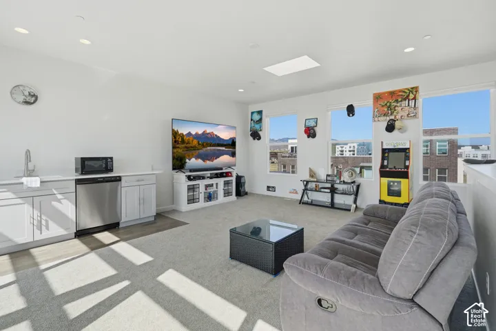 Open-concept living area with multiple windows, skylight, recessed lighting, and a built-in wet bar with stainless steel appliances