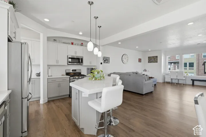 Open-concept living space featuring wood-finish flooring, recessed lighting, and large windows