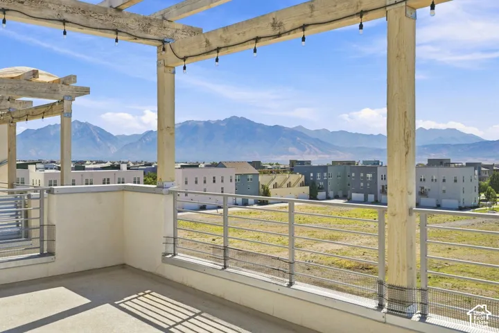 Rooftop deck featuring a wooden pergola, string lighting, and metal railings