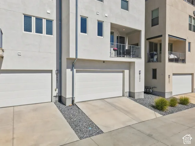 Modern stucco exterior with integrated garage doors, concrete driveways, and gravel landscaping