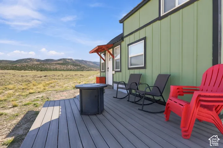 Expansive outdoor deck with composite decking, featuring a green vertical siding exterior, black framed windows, and a red awning above the entry
