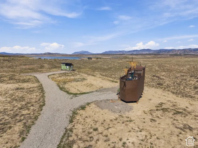 Expansive landscape featuring a unique boat-shaped structure, a separate green-sided outbuilding, and a gravel pathway