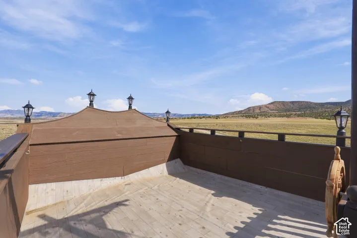 Deck with wood-finish flooring, featuring a unique ship-inspired design, decorative exterior lanterns, and expansive open-field scenery