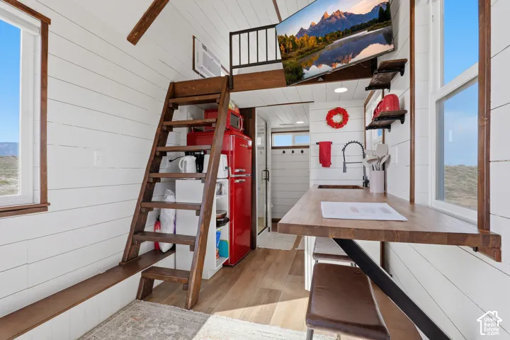 White shiplap walls, wood-finish flooring, a wood-finish countertop, an integrated ladder, and a built-in loft