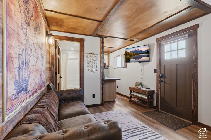 Wood-finish flooring, paneled ceiling, wood-trimmed doorways, and a solid entry door with window panes