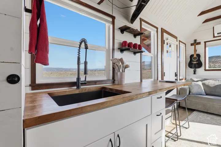 Integrated kitchen with a matte black faucet, single-basin sink, and wood-finish countertop