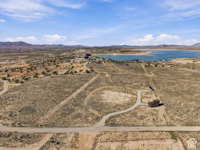 Expansive undeveloped land featuring a gravel road, distant lake, and surrounding natural topography