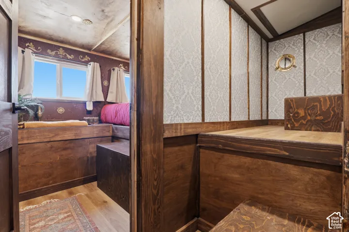Built-in wooden platform with integrated storage, wood-finish flooring, and decorative wall coverings