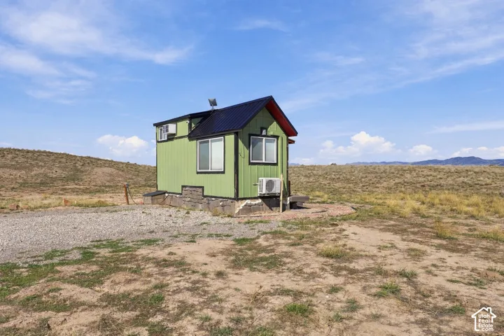Compact dwelling with green siding and a black metal roof