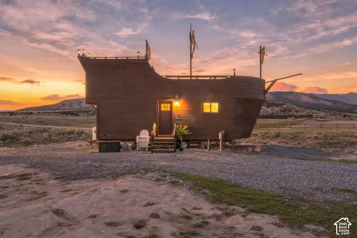 Unique boat-inspired structure featuring exterior lighting, multiple windows, and a prominent front door with steps