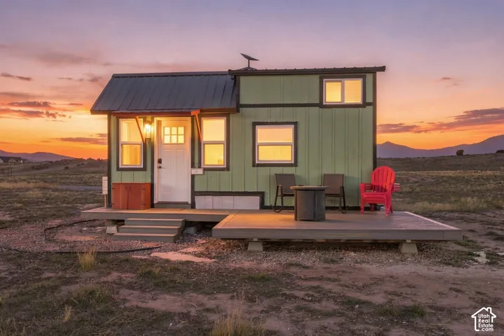 Green exterior siding with white trim, metal roofing, elevated deck, and front entry with steps
