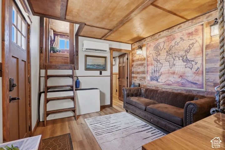 Wood-finish flooring with a wood plank accent wall, exposed beam ceiling, and a built-in ladder