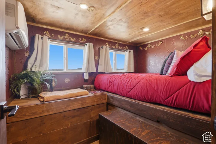 Built-in wood-finish platform bed with integrated storage, two windows, and ornate wall detailing