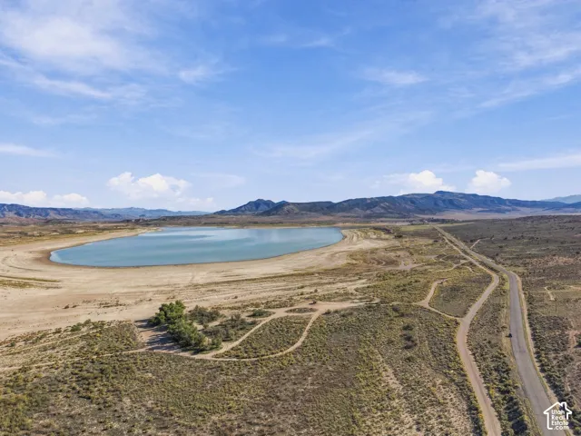Expansive land parcel featuring direct lake frontage, a paved road, and distant mountain backdrops