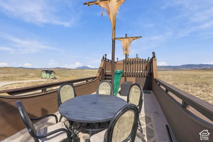 Expansive rooftop deck with panoramic scenery, featuring a brown railing and a green slide