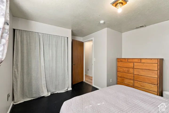 Dark flooring with light gray walls, an overhead ceiling light fixture, and a solid wood door frame