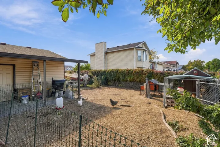 Expansive backyard featuring a covered patio, multiple fenced areas, and a structured outbuilding