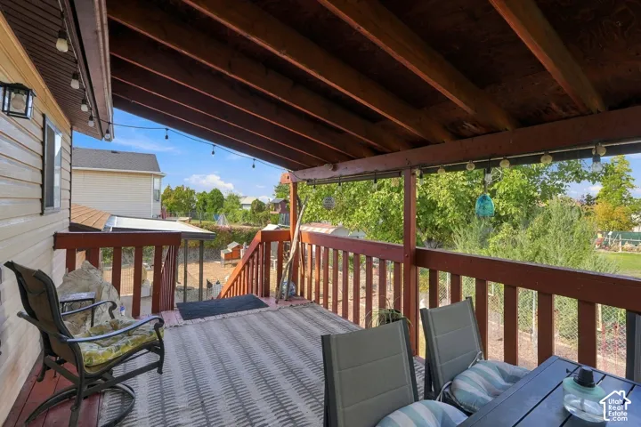 Expansive covered deck featuring composite decking, wood-beam ceiling structure, and wooden railings with vertical balusters