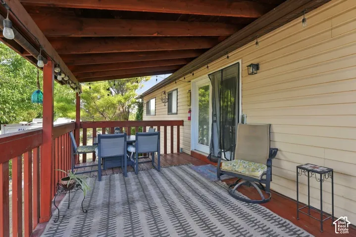 Covered outdoor deck with a wood ceiling, wood railing, and vinyl siding