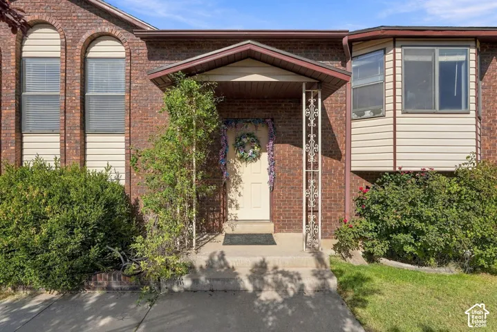 Brick exterior with arched windows, light-colored siding, covered entry, and bay window feature