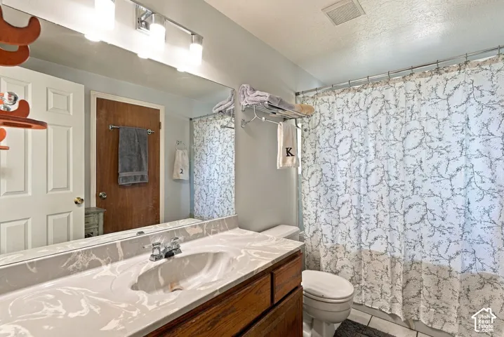 Bathroom featuring a single vanity with an integrated sink, patterned countertop, wood-finish cabinetry, and a chrome faucet