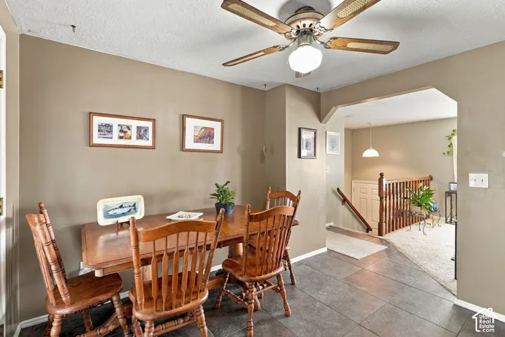 Dining area featuring a wood-finish ceiling fan with integrated lighting, tiled flooring, and an arched doorway