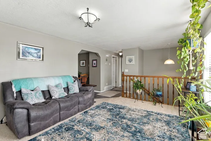 Recessed lighting and a decorative ceiling fixture illuminate this living area with neutral wall tones