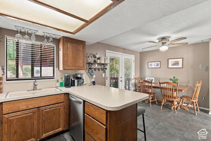 Kitchen featuring wood cabinetry, light-toned countertops, and a built-in stainless steel dishwasher