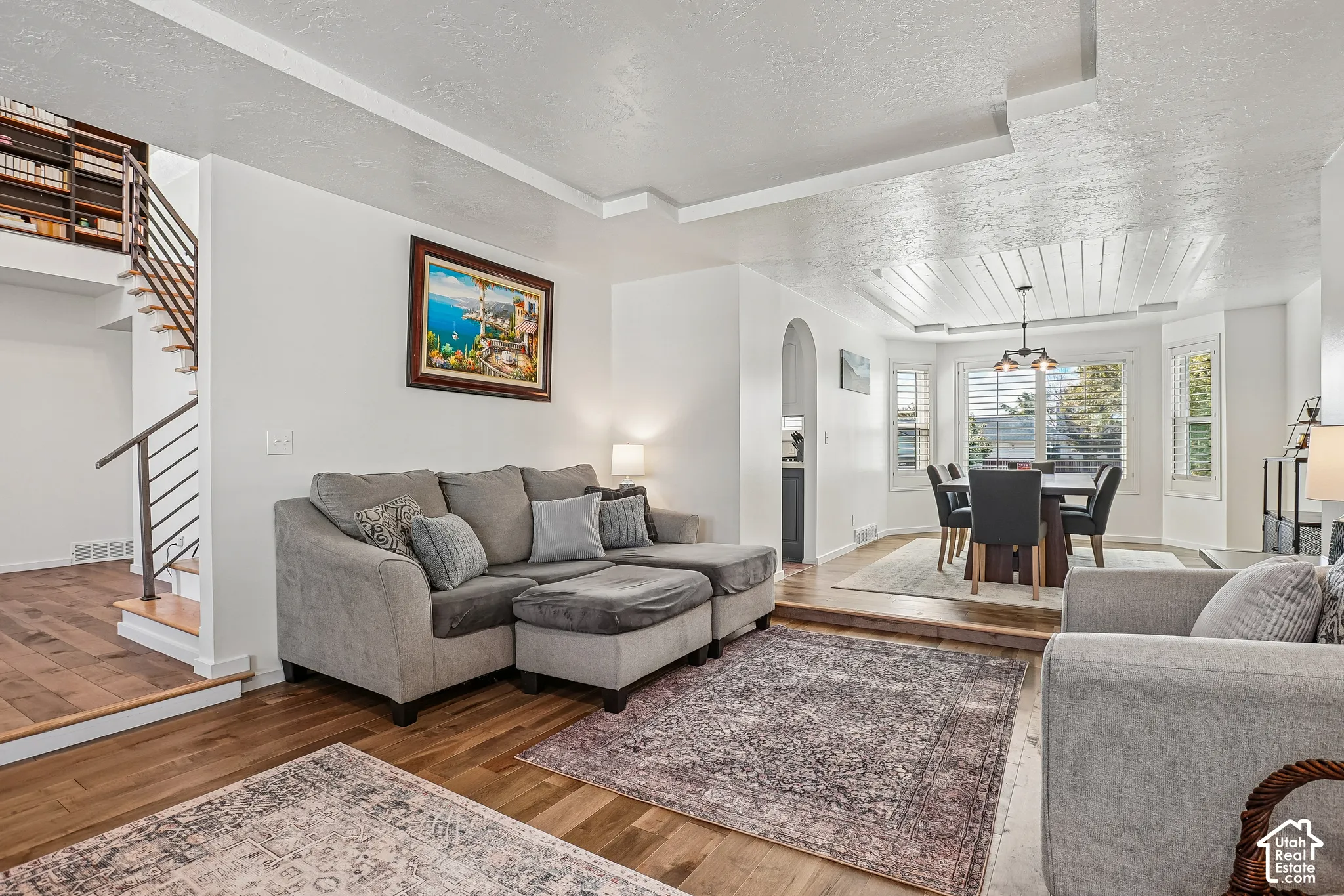 Hardwood-finish flooring, staircase with metal railings, arched doorway, recessed lighting, and a shiplap ceiling