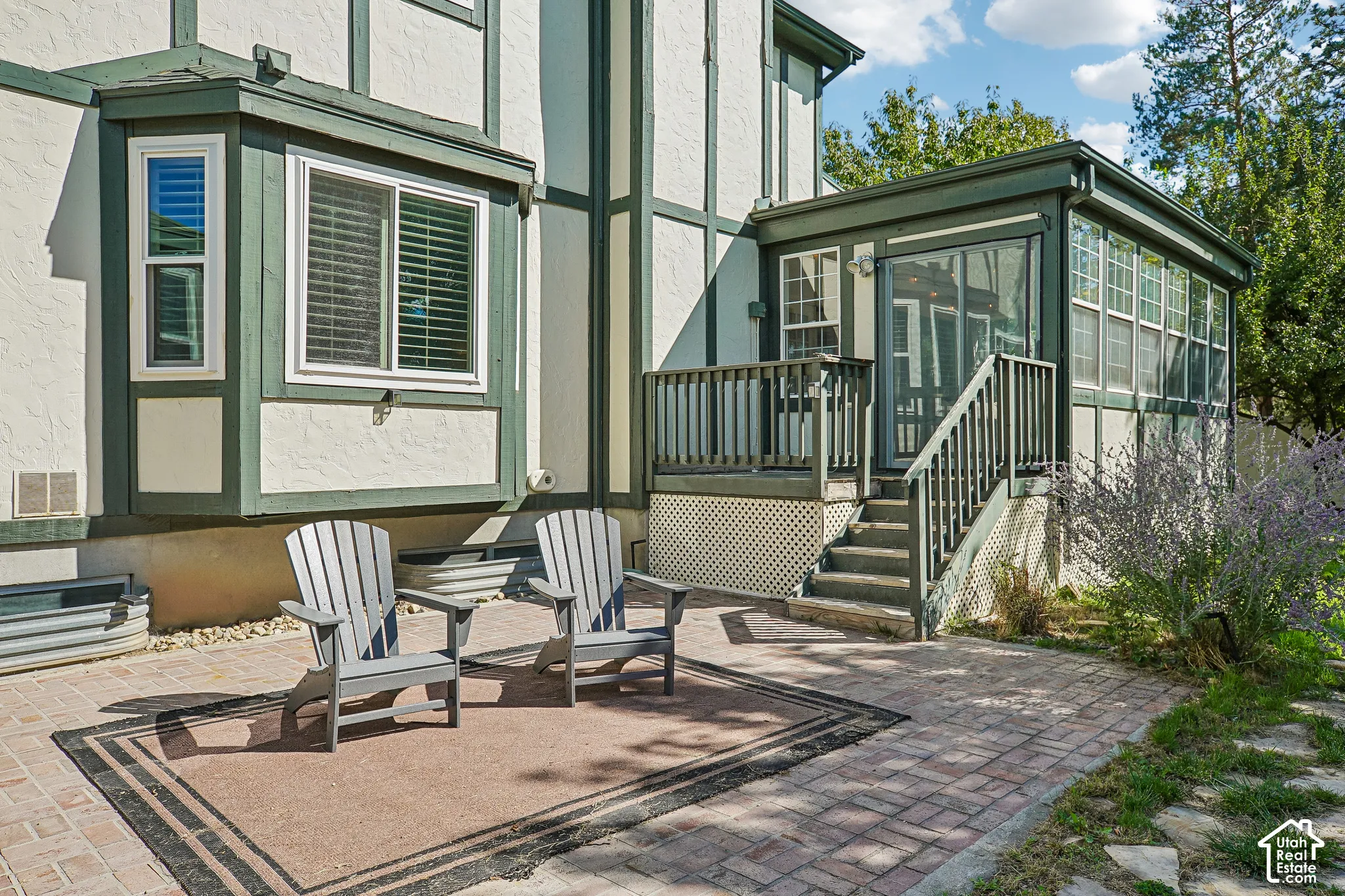 Brick paver patio featuring a sunroom, deck with railing, exterior steps, and a bay window