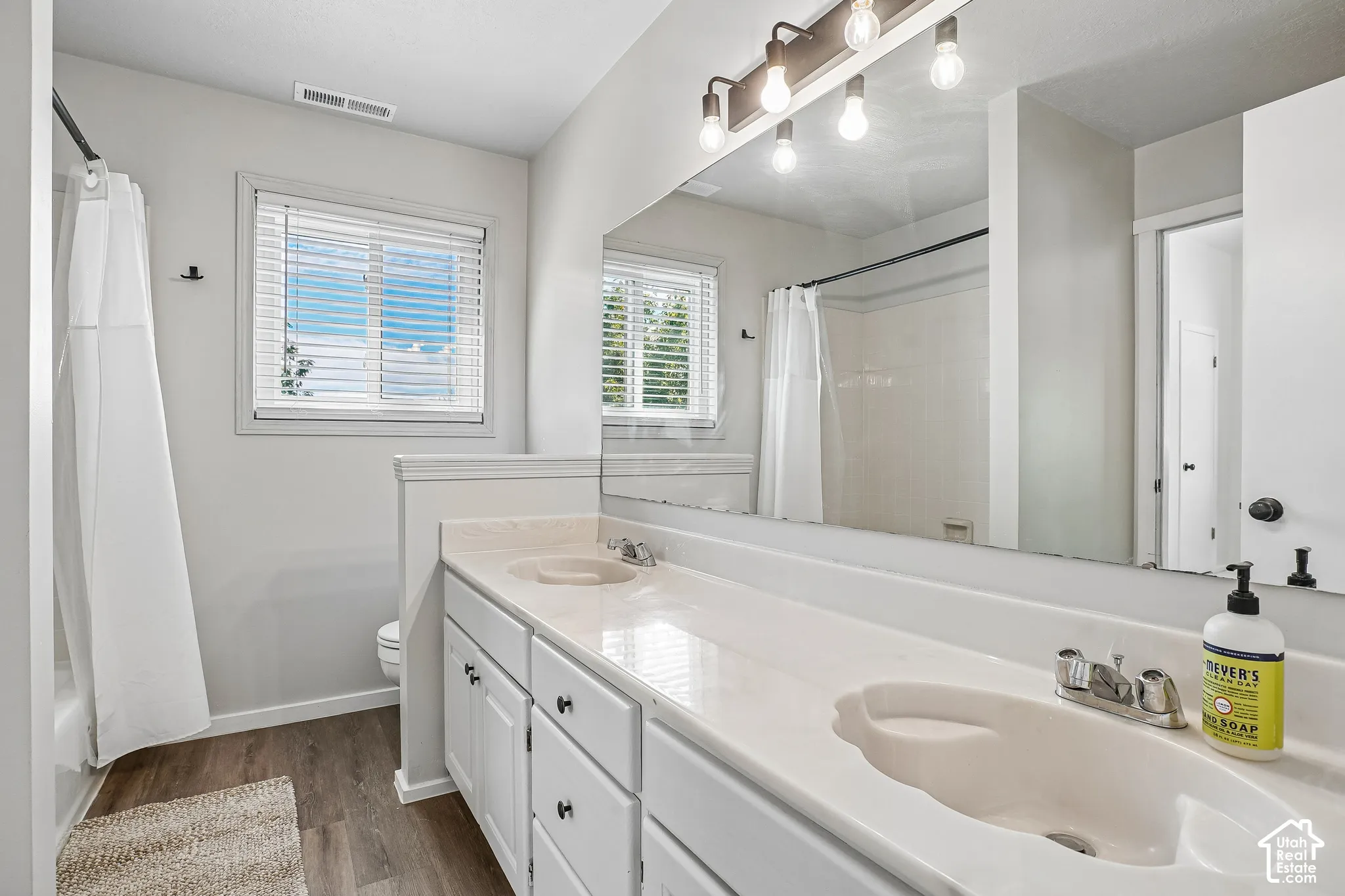 Double vanity with integrated sinks, white cabinetry, chrome fixtures, and a large mirror
