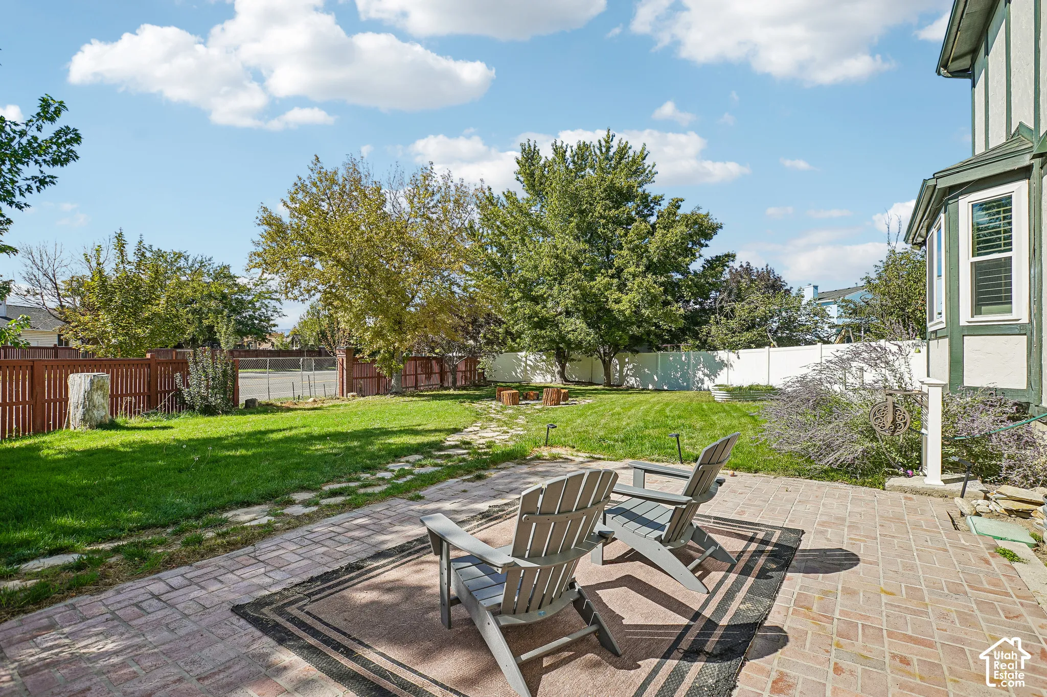 Brick paver patio with a bay window, expansive lawn, and wood privacy fencing