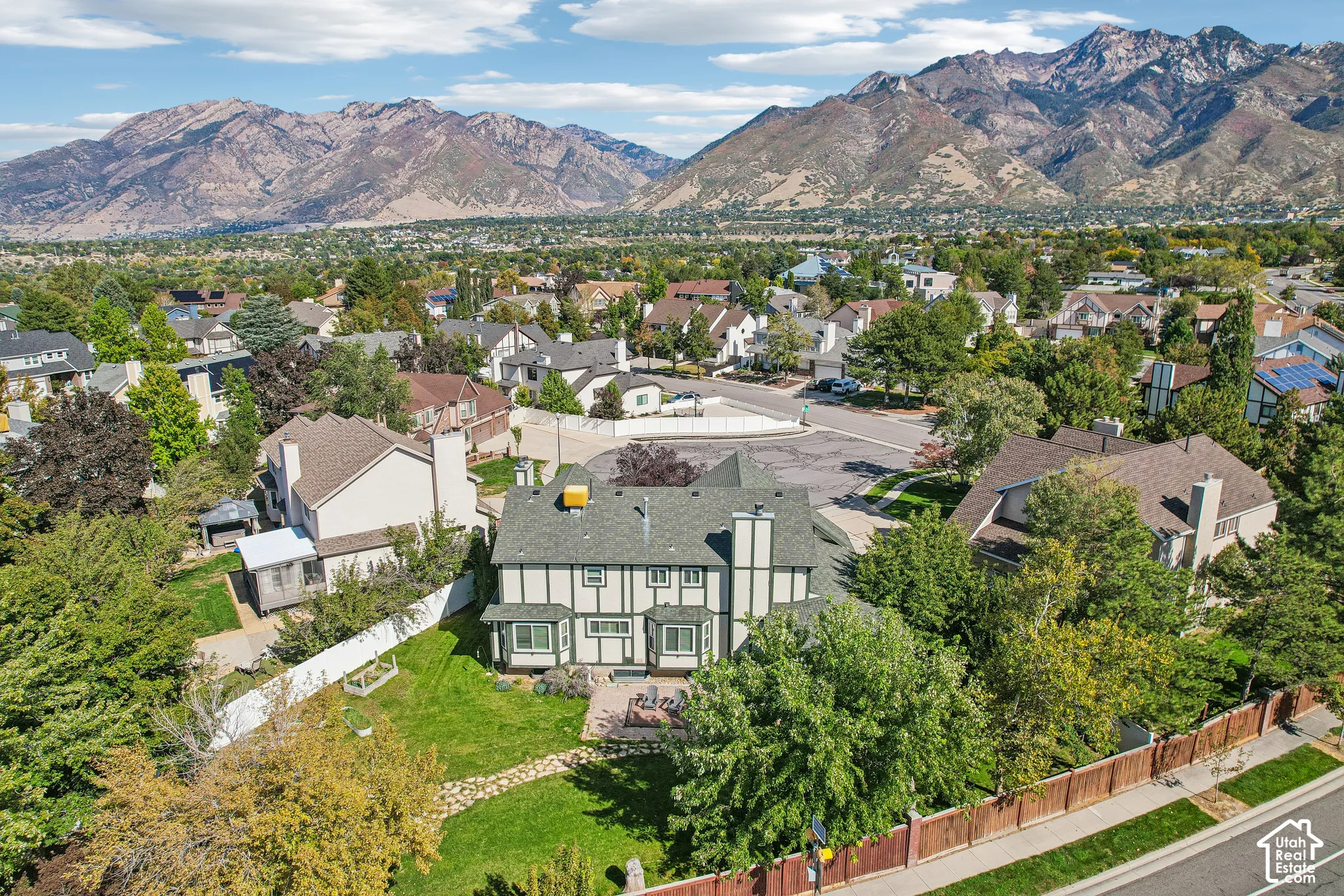 Tudor-style residence with a distinct exterior, mature landscaping, and a stone patio