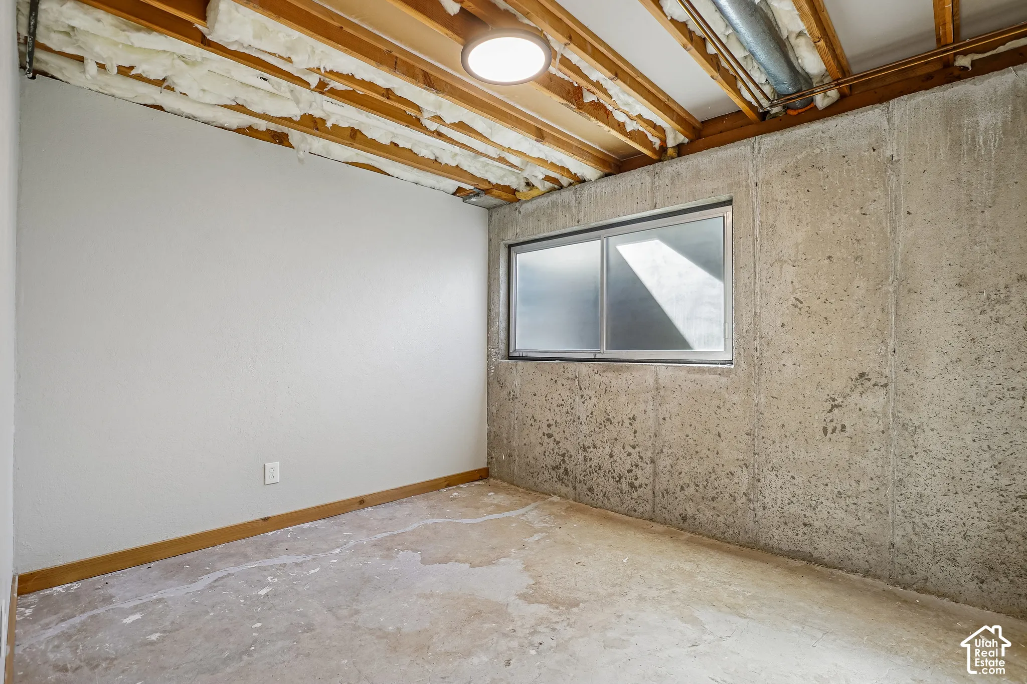 Unfinished concrete flooring, painted drywall, and a horizontal sliding window