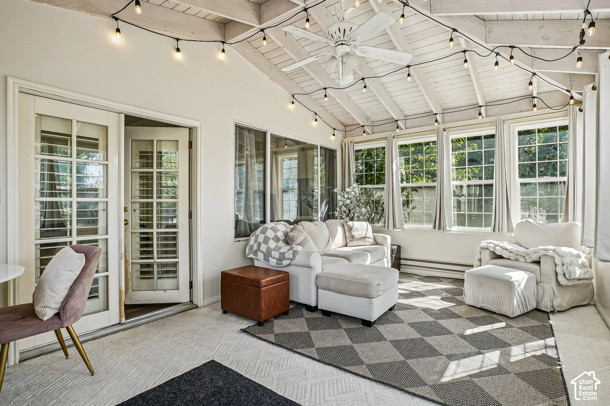 Vaulted wood-paneled ceiling, multiple large windows, glass-paneled French doors, ceiling fan, and textured flooring