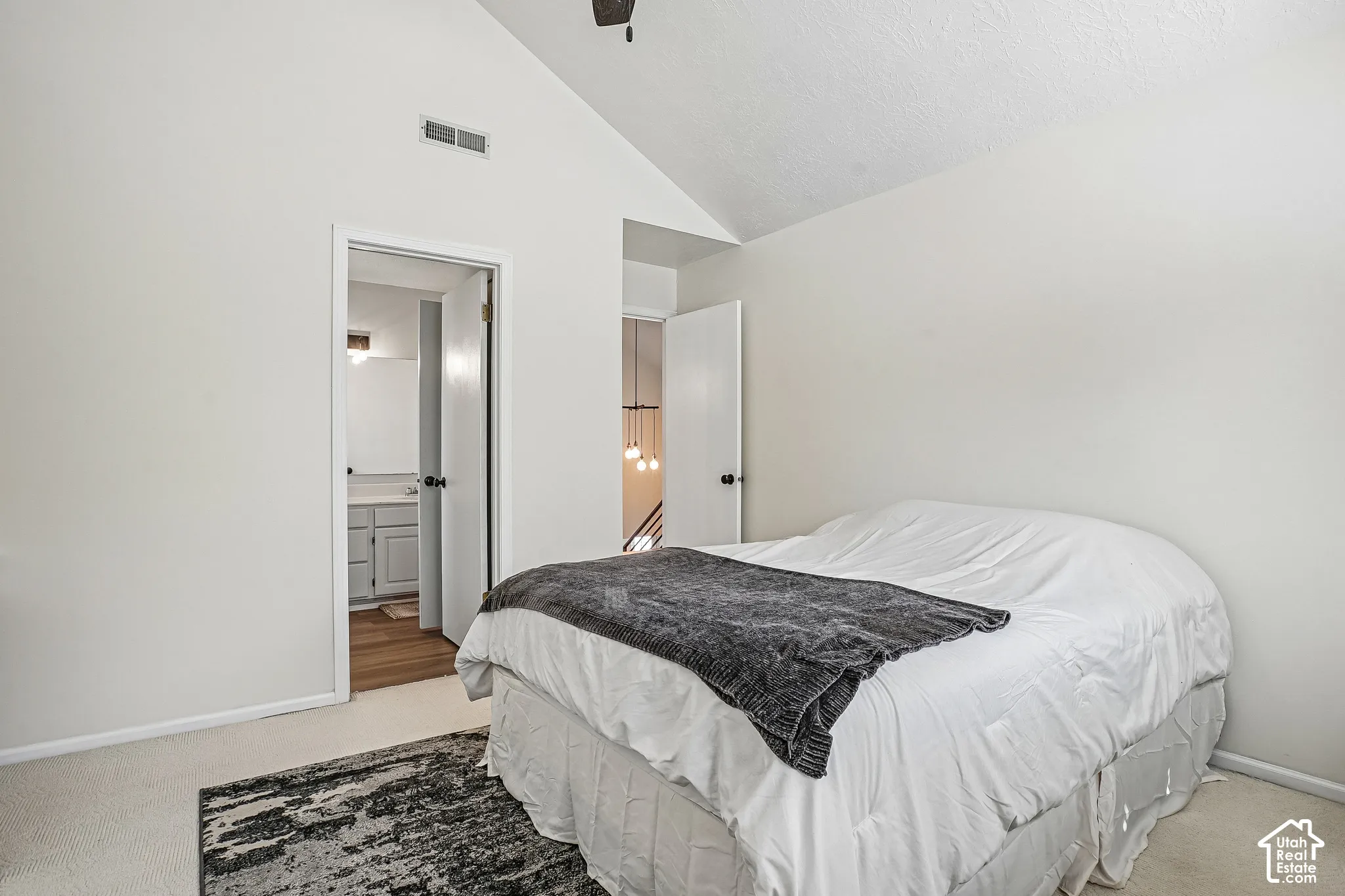 Vaulted ceiling with a ceiling fan, white walls, and a light-colored carpeted floor