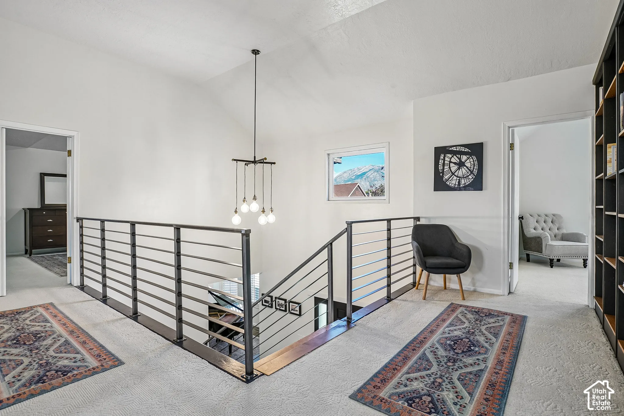 Open-concept upper landing featuring a vaulted ceiling and a contemporary chandelier
