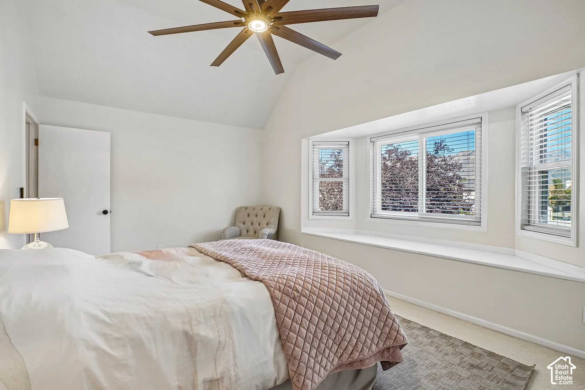 Vaulted ceiling with a ceiling fan, bay window with a built-in window seat, and neutral-toned carpet flooring