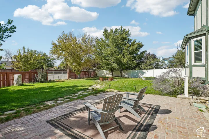 Brick paver patio with a bay window, expansive lawn, and wood privacy fencing