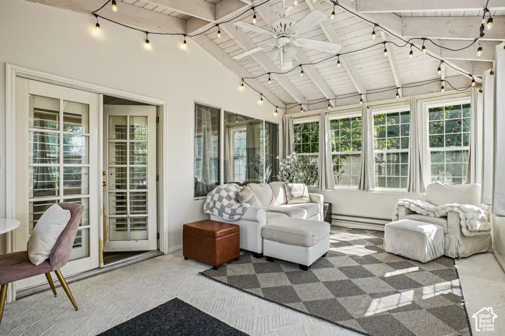 Vaulted wood-paneled ceiling, multiple large windows, glass-paneled French doors, ceiling fan, and textured flooring
