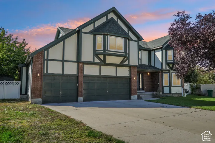 Tudor-style exterior with brick and stucco siding, multi-pane windows, multiple gables, and an attached two-car garage