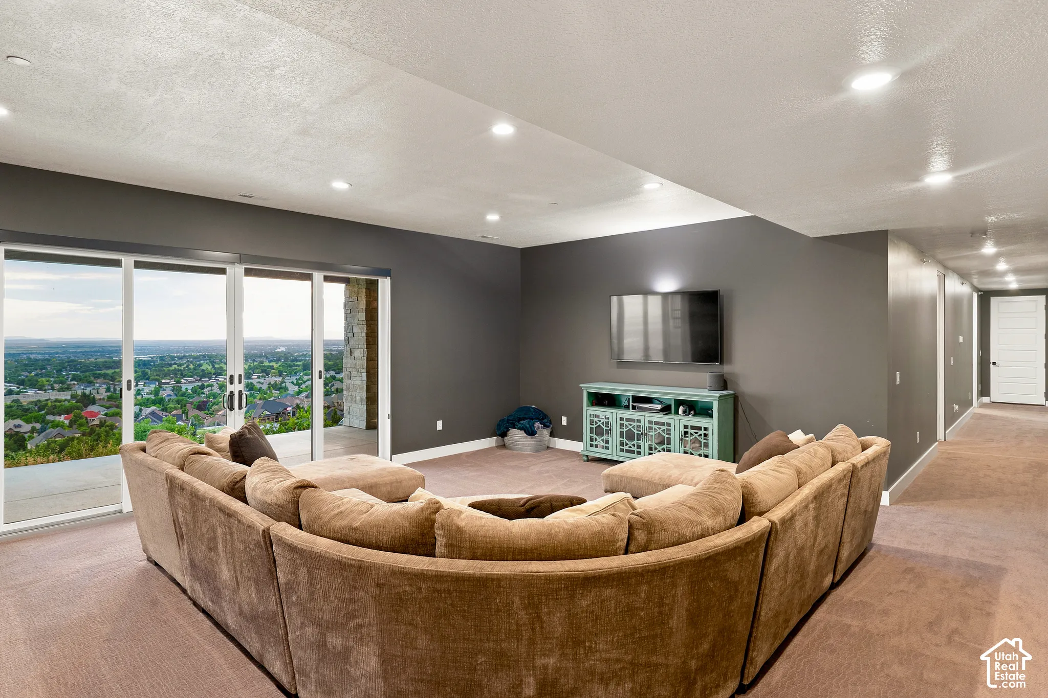 Recessed lighting, sliding glass doors, dark accent wall, carpeted flooring, and a long hallway