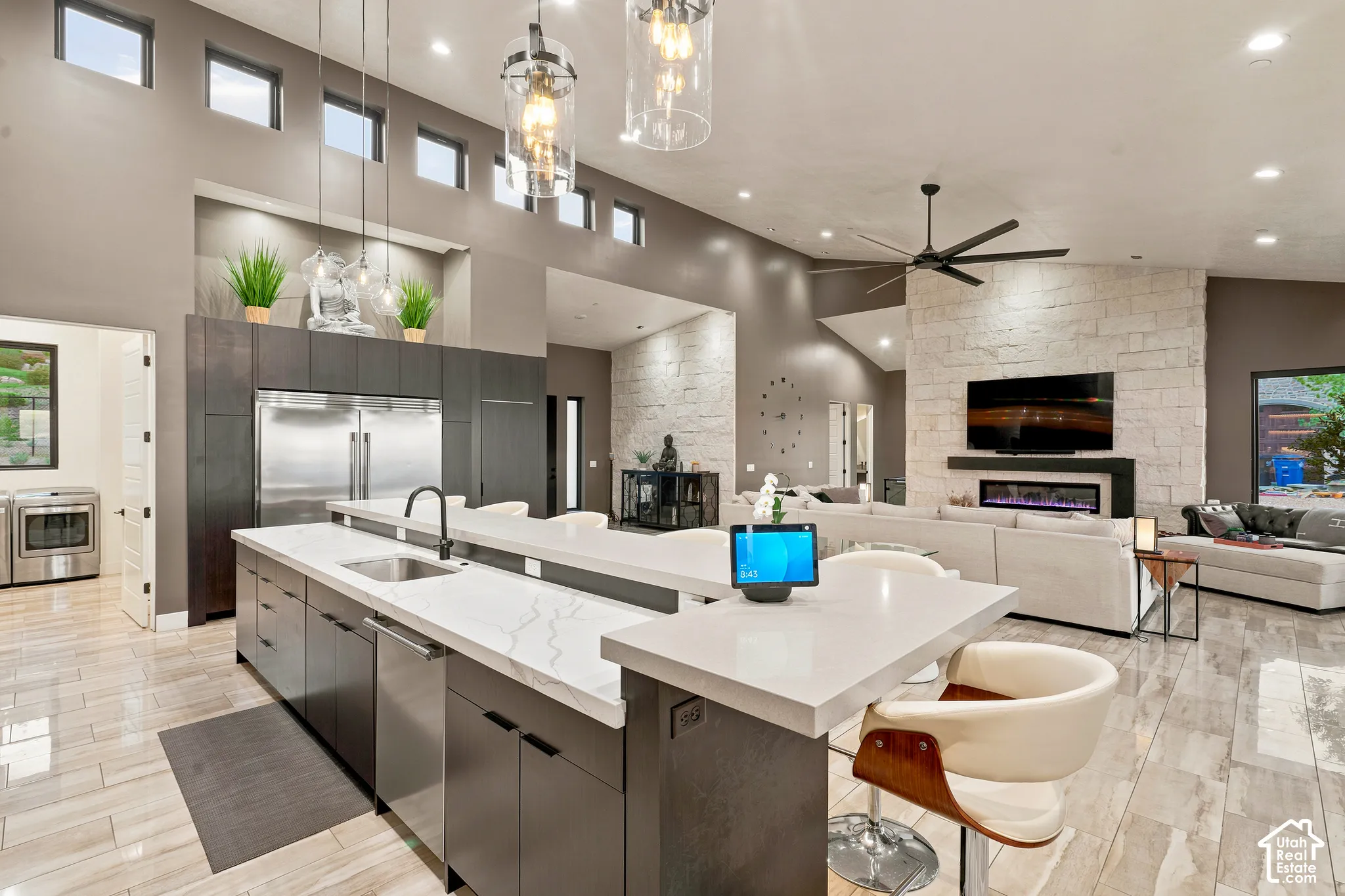 Open-concept living area featuring a large kitchen island with a built-in sink, stainless steel appliances, and wood-finish flooring