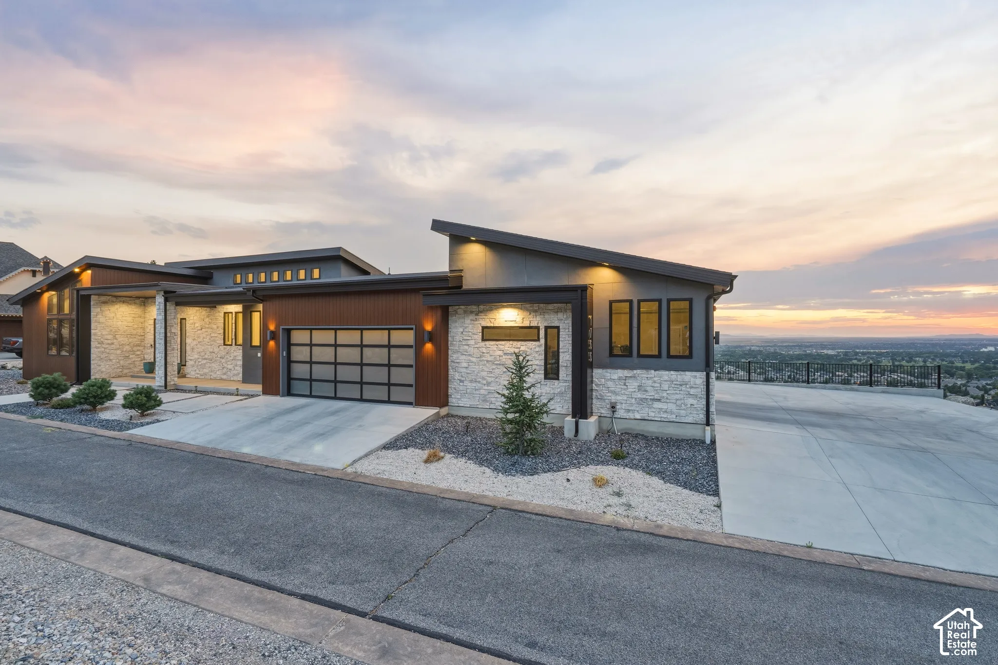 Modern architectural exterior featuring stone veneer, horizontal wood-finish siding, and a contemporary frosted-panel garage door